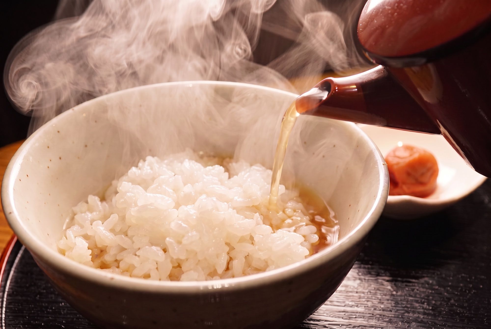 湯気の立つご飯に汁を注ぐ